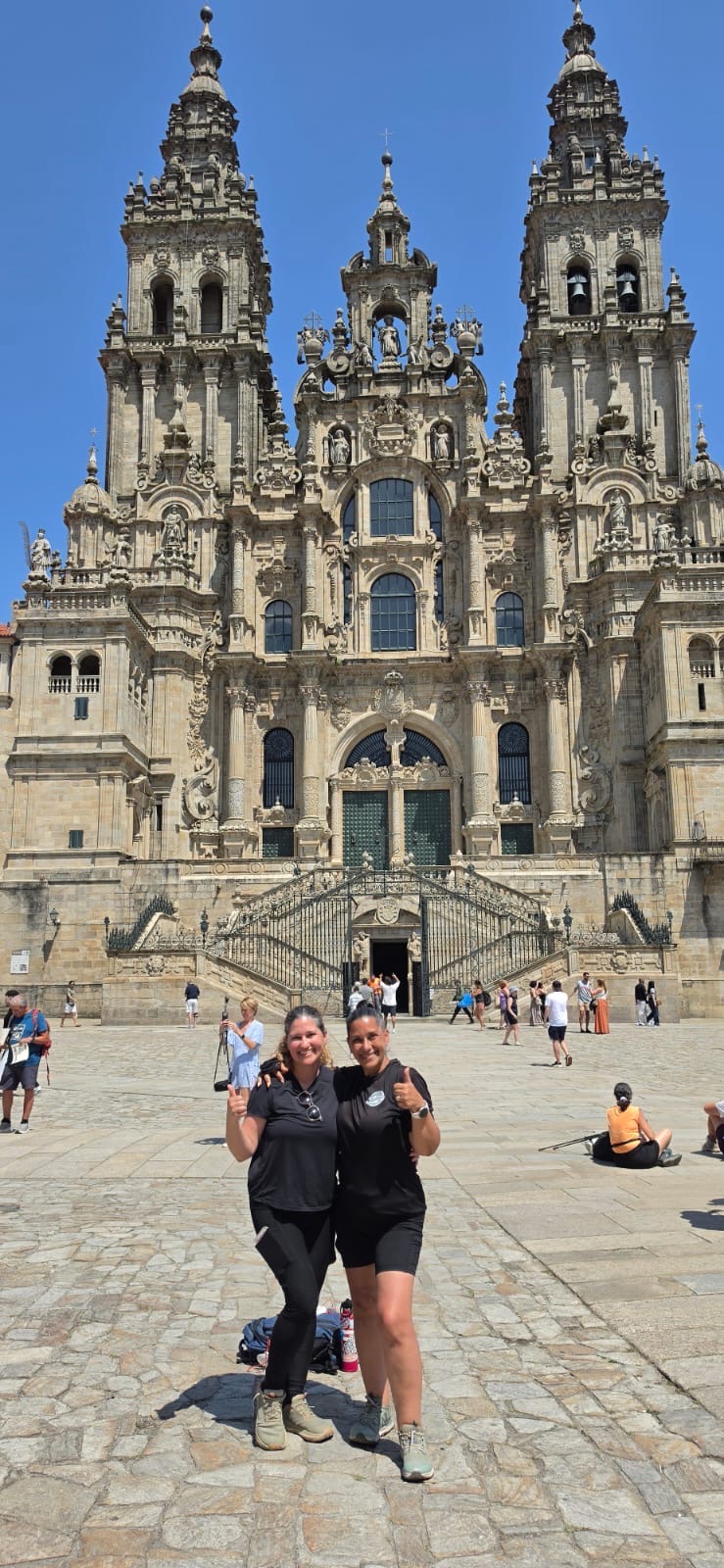 Two pilgrims celebrating together in the plaza outside the Cathedral of Santiago