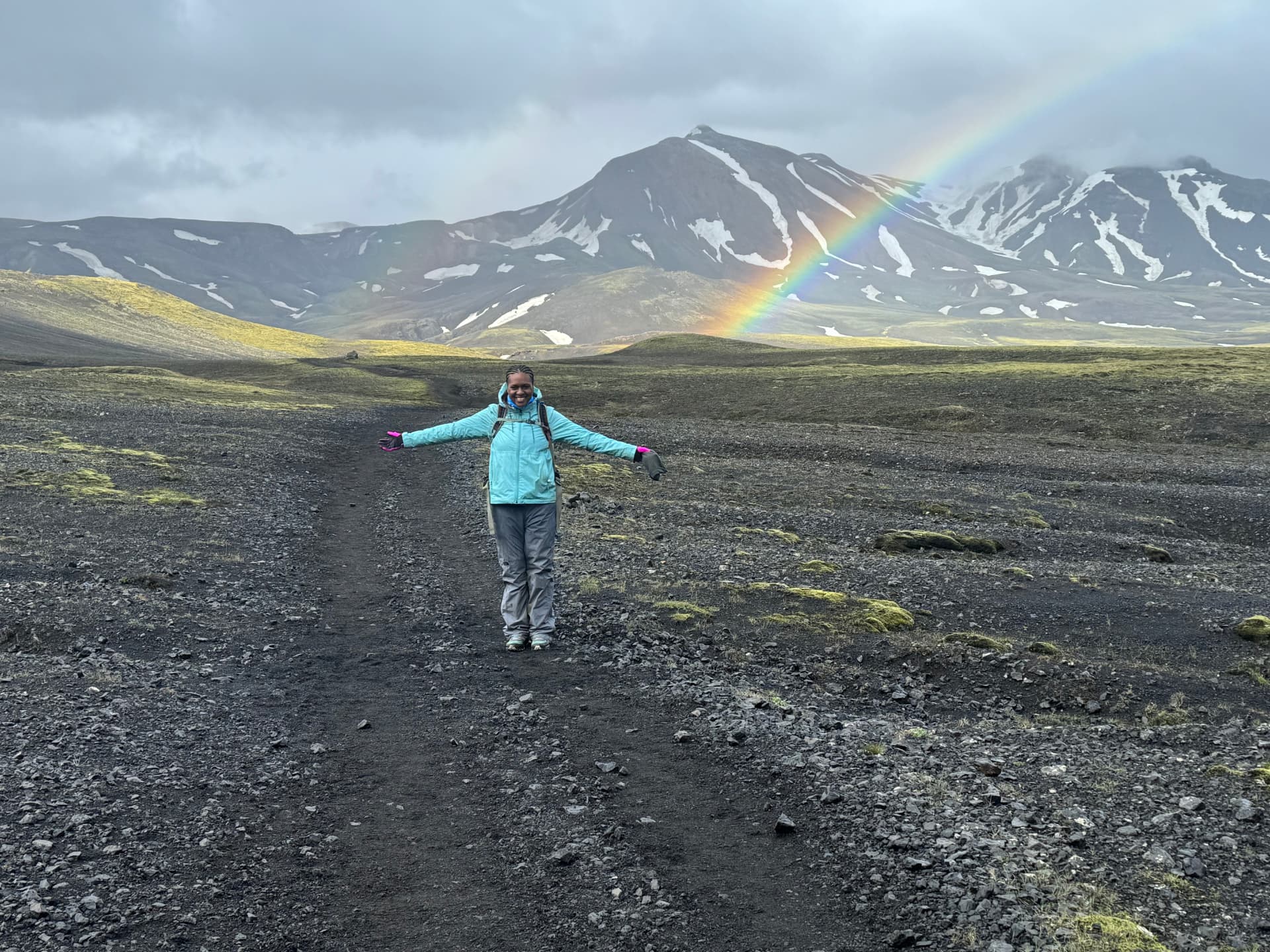 Yasmeen Harris-Youngblood standing on the Laugavegur Trail in Iceland with a rainbow over the mountains