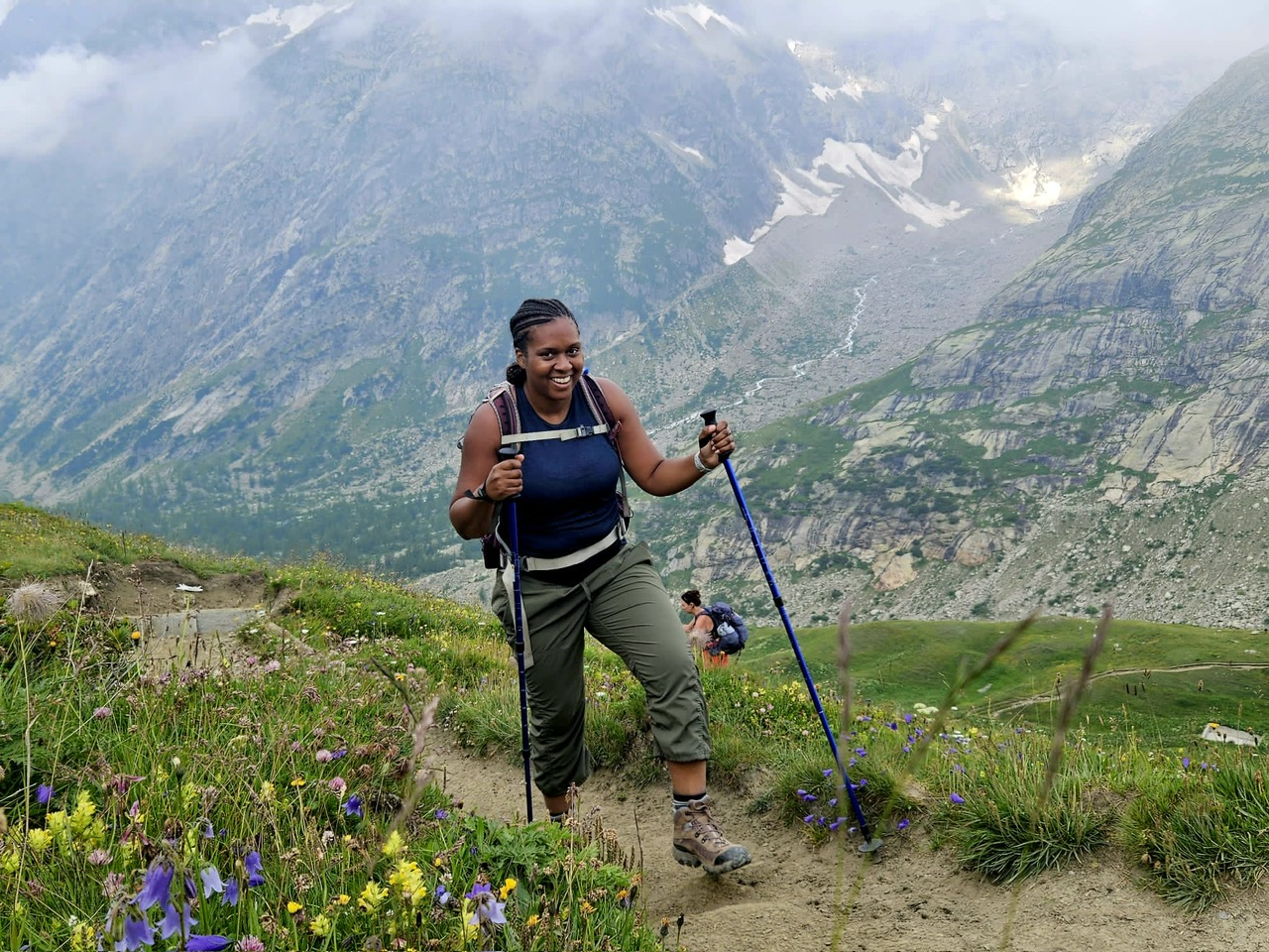 Yasmeen Harris-Youngblood hiking a wildflower-lined alpine trail in the mountains