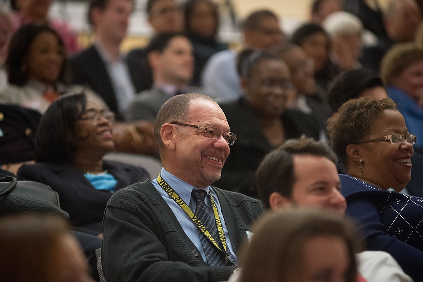 A diverse audience of educators smiling and listening during a professional development session